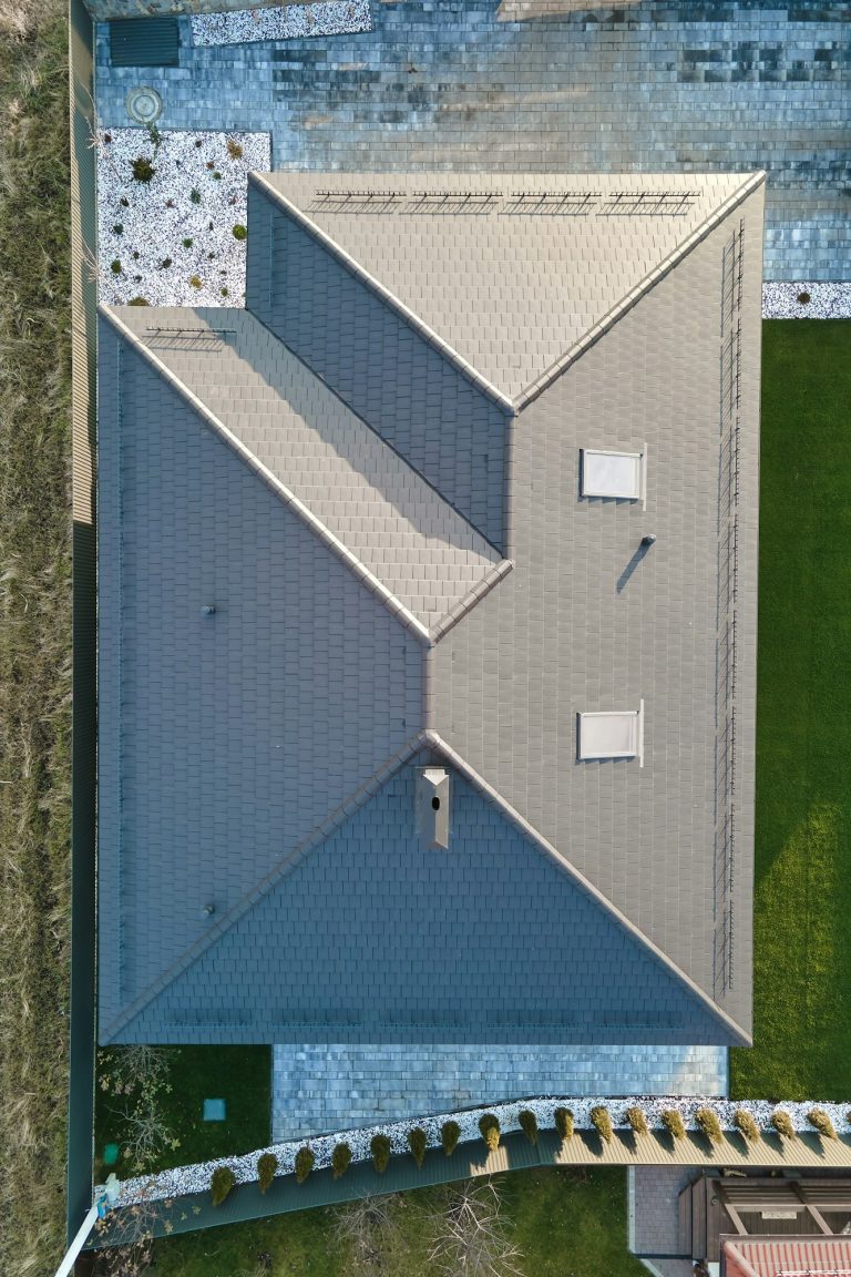 Aerial view of house roof top covered with ceramic shingles. Tiled covering of building under